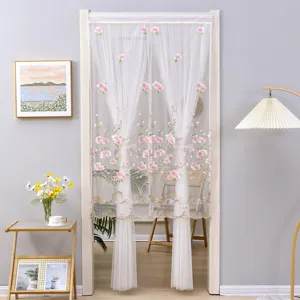 Detailed scene of white mesh embroidered door curtain with pink floral design in room.