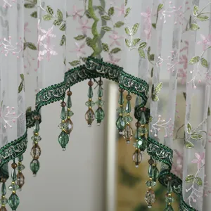 Close-up of French lace short curtain, exquisite pink floral embroidery and green beaded fringe.