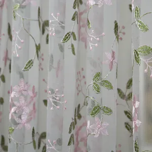 Close-up of sheer curtain featuring pink floral embroidery and fine mesh fabric design.