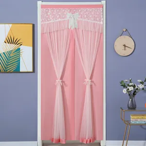 Close-up of pink lace door curtain featuring delicate floral embroidery and bows.