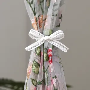 French romantic floral embroidered sheer curtain detail showcasing lace bow tie and fine mesh fabric.