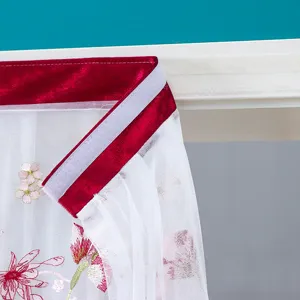 Vue rapprochée du rideau de porte en tulles blancs avec bordure en velours rouge et broderie.