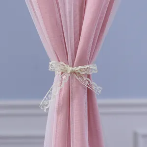 Close-up detail of a pink tulle curtain with a delicate lace bow tie for room decor.