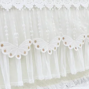 Primer plano de funda de cabecera de encaje blanco con mariposas bordadas y tul.