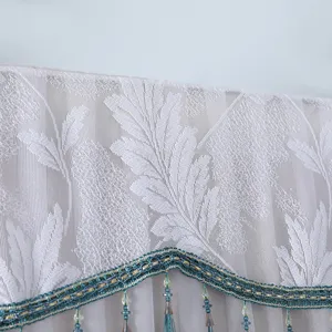 White lace refrigerator cover detail showing delicate leaf pattern and decorative fringe trim.