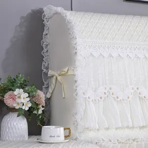 Funda protectora acolchada de encaje para cabecera de cama en elegante tela blanca.