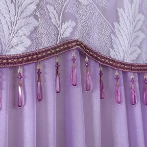 Close-up detail of purple lace fabric with white leaf pattern and elegant crystal bead fringe.