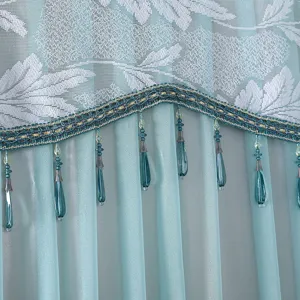 Detailed view of blue lace refrigerator cover or curtain with white floral pattern and beaded fringe