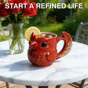 Red cardinal bird ceramic mug with feather handle on a marble table outdoors
