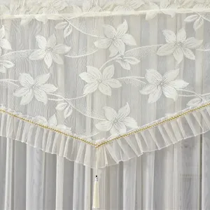 Detailed view of white lace curtain fabric with floral pattern and delicate ruffles.