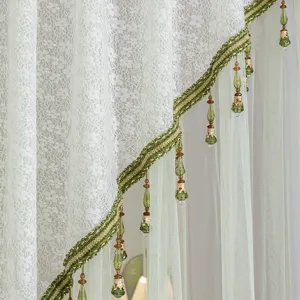 Close-up detail of light green lace curtain with beaded fringe tassel. Soft texture design.