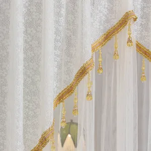 White lace curtain with gold trim and yellow crystal pendants for home bedroom decor detail.