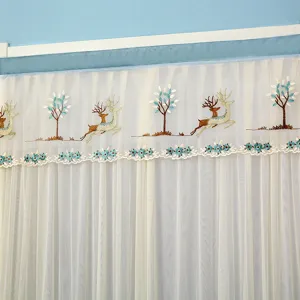 Detail shot of sheer curtain top featuring cute embroidered deer, trees and blue lace trim.