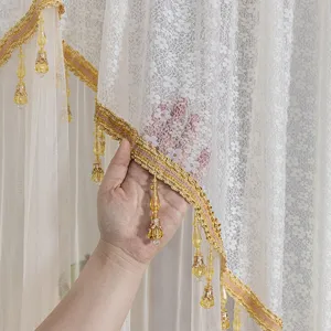 White lace door curtain detail with gold trim and crystal pendants for bedroom and home decor.