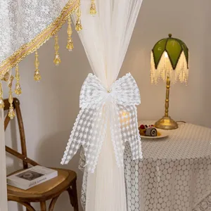 Elegant lace door curtain with delicate bow tieback and gold beaded tassels for home decor.