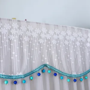 White lace refrigerator dust cover detail showing delicate floral pattern and beaded fringe.