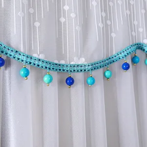 Detail shot of white lace dust cover showing exquisite blue braided trim and bead pendants.