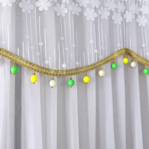White lace dust cover detail with floral pattern, gold braided trim, and colorful beads.