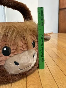 Detail view of plush cow Easter basket measured with a ruler for product scale
