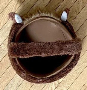 Detailed top view of a soft brown plush cow Easter basket featuring horns and fur tuft