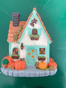Nahaufnahme eines weißen Miniaturhauses mit Kürbissen für die Halloween-Deko