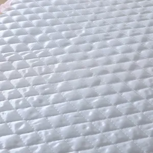 Nahaufnahme des Details von weißem gesteppten Waschmaschinenbezug mit Rautenmuster.