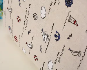 Detalle de primer plano de funda de portatil de lino con estampado marino de veleros.