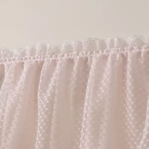 Gros plan d'un tissu en dentelle à pois rose doux avec un délicat design de bordure à volants.
