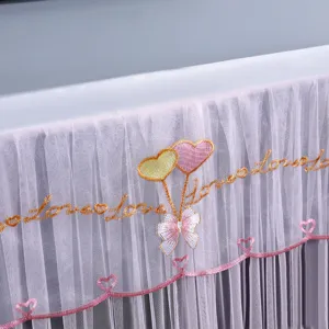 Primo piano della copertura antipolvere per TV in pizzo rosa con cuori ricamati e testo.