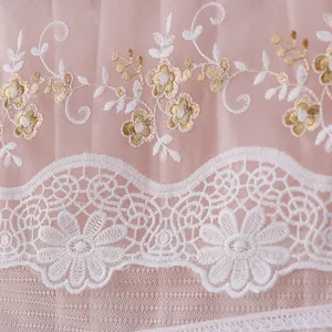 Detailed view of pink mesh fabric with elegant white and gold floral embroidery and lace.