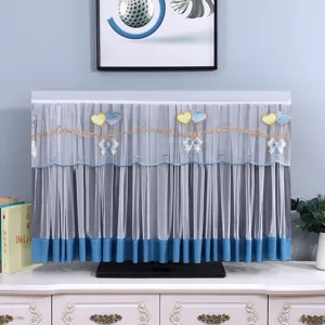 Dettaglio copertura antipolvere TV in pizzo con delicato ricamo a cuore e bordo blu.