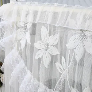 Detailansicht der weißen Spitzen-Waschmaschinen-Staubabdeckung mit Blumenmuster.