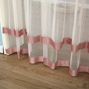 Detail shot of white sheer door curtain featuring elegant pink satin ribbon trim at bottom.