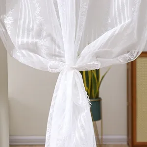 Close-up detail view of elegant white lace sheer curtain tieback for room door privacy.