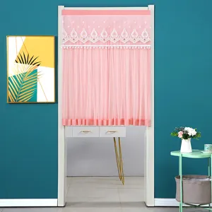 Pink door curtain scene with delicate lace embroidery and tassels in a cozy home.