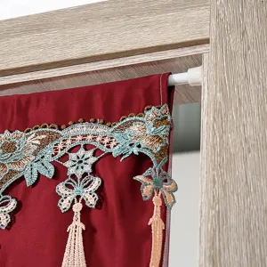 Primo piano dettagliato della tenda rossa elegante con ricamo in pizzo e nappe pendenti.