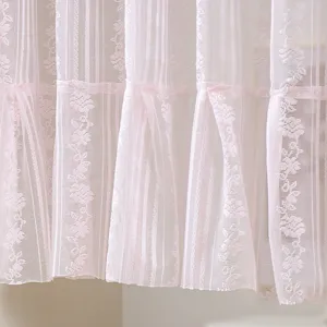 Close up detail of soft pink lace curtain fabric with vertical stripes and floral patterns.