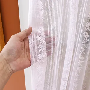 Close-up detail of white lace door curtain, sheer fabric with floral pattern for bedroom.