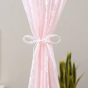 Close-up detail of pink lace curtain with white bow tie, delicate textured sheer fabric.