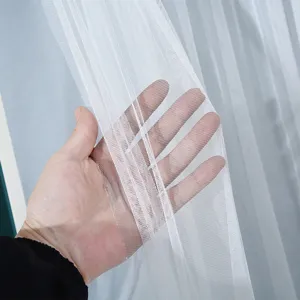 White sheer curtain mesh fabric detail showing texture and light transmittance close up.