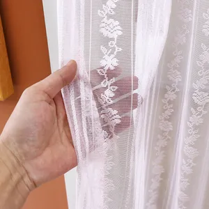 Close-up view of pink lace curtain fabric texture, delicate floral pattern mesh design detail.