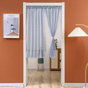 Detail shot of the elegant blue-grey lace door curtain hanging in a cozy home scene.