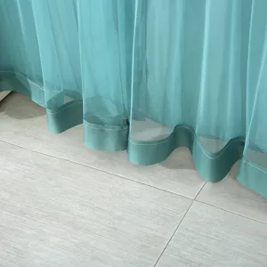 Close-up teal sheer curtain hem and fine stitching showing elegant drape and fabric texture.