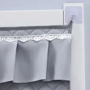 Dettaglio tenda trapuntata grigia con delicato bordo in pizzo bianco e gancio adesivo.