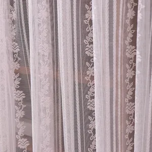 White lace fabric detail showing sheer curtain texture with elegant vertical floral patterns.