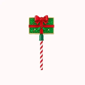 Detail des Weihnachtszauberstabs mit grüner Geschenkbox, roter Schleife und Zuckerstangenstab.