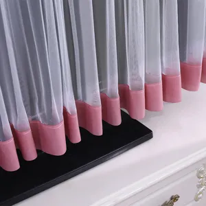 Vista dettagliata della copertura antipolvere TV in pizzo bianco con orlo rosa.