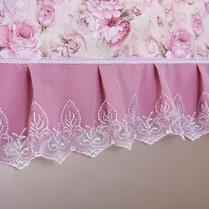 Detailansicht der rosa Blumenstaubabdeckung mit Plissee-Rüsche und weißer Spitzenstickerei.
