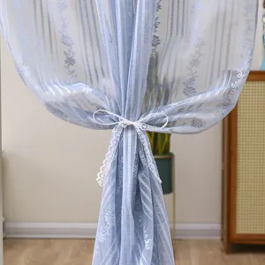 Close-up of blue lace sheer curtain detail featuring elegant floral stripes and white tie.