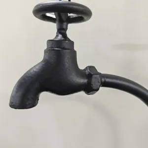 Close-up detail of the vintage black metal faucet-shaped garden bird feeder decoration